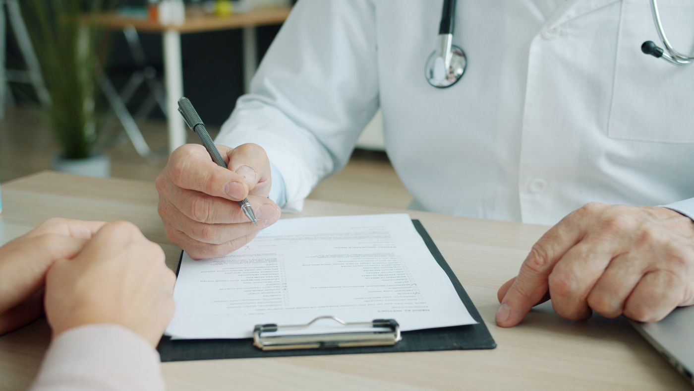 Doctor and patient reviewing health coverage documents together